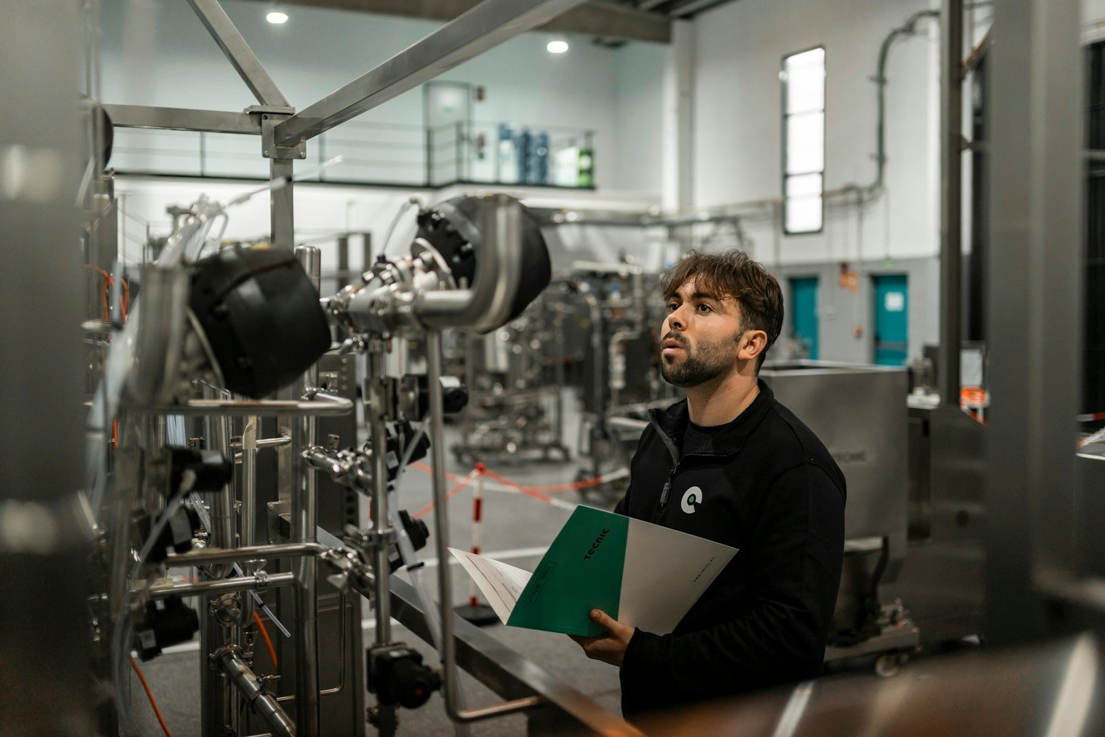 Engineer inspecting industrial equipment with technical documentation